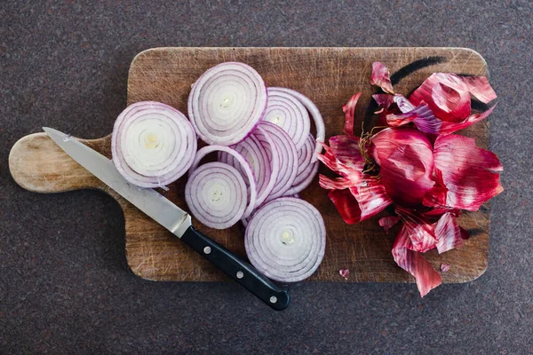 Basit gıda malzemeleri konsepti, kırmızı soğan ya da İspanyol soğanı mutfak tezgahının kırsal ahşap kesim tahtasının üzerinde halka şeklinde doğranmış.