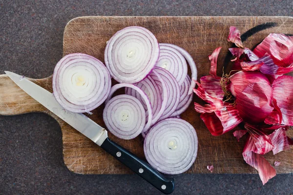 Basit gıda malzemeleri konsepti, kırmızı soğan ya da İspanyol soğanı mutfak tezgahının kırsal ahşap kesim tahtasının üzerinde halka şeklinde doğranmış.