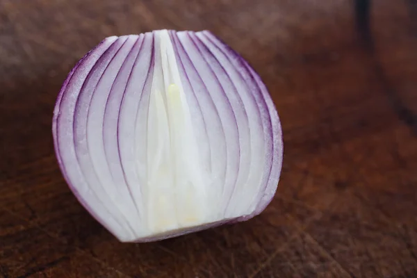 simple food ingredients concept, close up of half of red onion on wooden cutting board