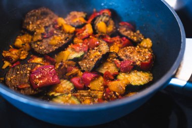 Sağlıklı bitkisel yemek tarifleri konsepti, vegan patlıcan kabağı ve kırmızı biber karışımı karışık baharat ve taze domatesle tavada soteleniyor.