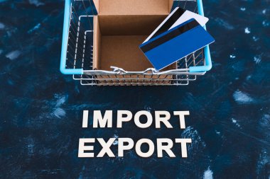 Uluslararası ticaret ve küresel iş konsepti, alışveriş sepetinin yanına açık paket kutusu ve kredi kartlarıyla ithalat metni