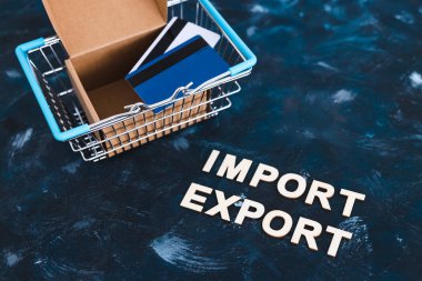 Uluslararası ticaret ve küresel iş konsepti, alışveriş sepetinin yanına açık paket kutusu ve kredi kartlarıyla ithalat metni