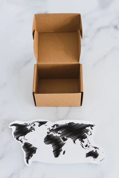 concept of global trade and worldwide deliveries, miniature postal parcel next to world map