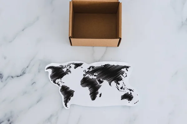 concept of global trade and worldwide deliveries, miniature postal parcel next to world map