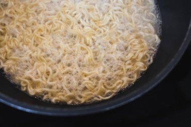 Basit gıda malzemeleri konsepti, erişteler mutfak ocağında tavada pişiyor.