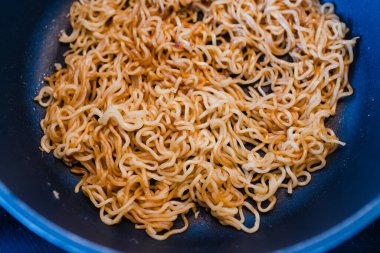 Basit gıda malzemeleri konsepti, erişteler mutfak ocağında tavada pişiyor.