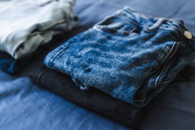 Gardırobunu düzenlemek ve düzenlemek, farklı kot renkleri olan farklı kotlar yığınlar halinde sıralanıyor.