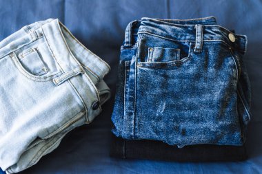 Gardırobunu düzenlemek ve düzenlemek, farklı kot renkleri olan farklı kotlar yığınlar halinde sıralanıyor.