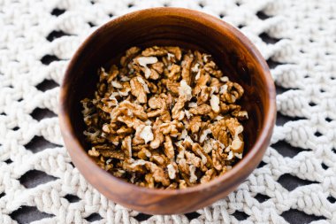 Basit gıda malzemeleri konsepti, ahşap kasede ceviz taneleri ve makrome kaplar.