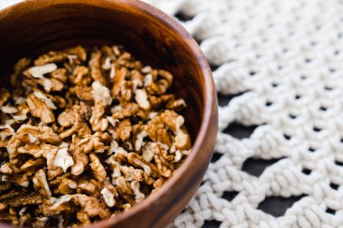 Basit gıda malzemeleri konsepti, ahşap kasede ceviz taneleri ve makrome kaplar.