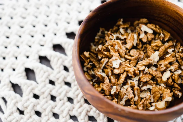 Basit gıda malzemeleri konsepti, ahşap kasede ceviz taneleri ve makrome kaplar.