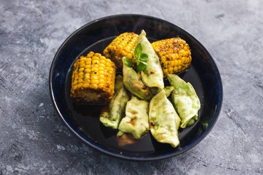 sağlıklı bitkisel yemek tarifleri konsepti, koçanlarında ızgara mısır olan sebze gyoza.