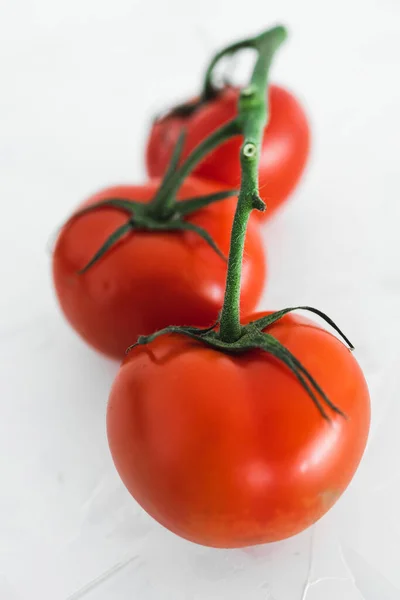 シンプルな食材と食べ物の食事の概念白のミニマリストの背景に3つのトマトのクローズアップ — ストック写真