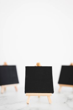beyaz mermer masadaki minyatür sehpalarda üç siyah tuval, metin veya tasarım eklemek için minimalist model arka plan, sığ dof