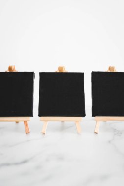 beyaz mermer masadaki minyatür sehpalarda üç siyah tuval, metin veya tasarım eklemek için minimalist model arka plan, sığ dof