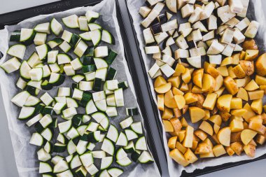 Yanyana iki fırın tepsisi, yanında çiğ kabak, patlıcan, sağlıklı vejetaryen yemek hazırlama teması.