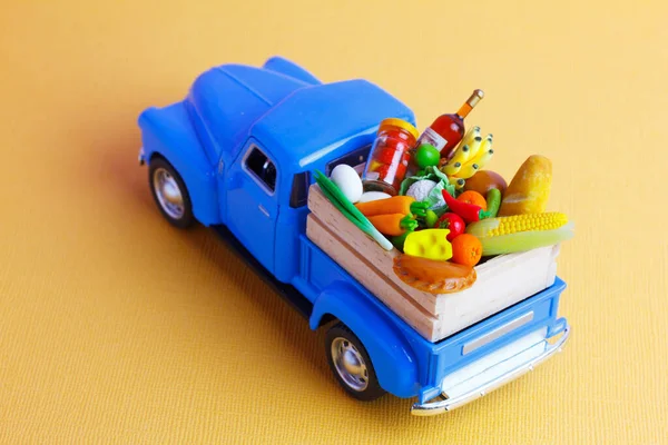 Blue toy  car  carries food and drinks in a wooden box. Food delivery concept.