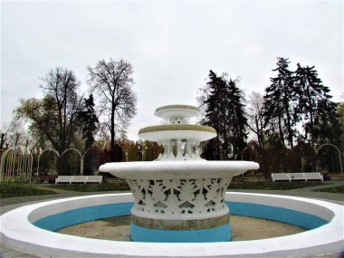 Bulutlu bir günde sonbaharın arka planında beyaz bir çeşme.