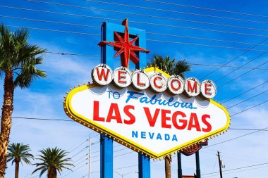 Las Vegas 'ın parlak güneşli günündeki Muhteşem Las Vegas tabelasına hoş geldiniz. Arka planda Las Vegas' ın kalbinin olduğu Las Vegas, Nevada 'nın Uykusuz Şehri tabelasına hoş geldiniz..