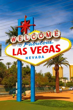 Las Vegas 'ın parlak güneşli günündeki Muhteşem Las Vegas tabelasına hoş geldiniz. Arka planda Las Vegas' ın kalbinin olduğu Las Vegas, Nevada 'nın Uykusuz Şehri tabelasına hoş geldiniz..