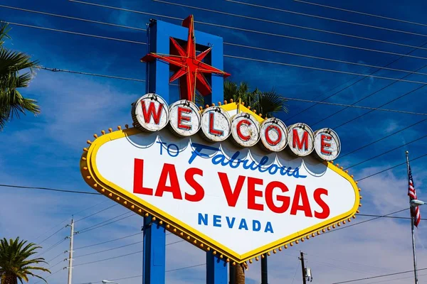 Las Vegas 'ın parlak güneşli günündeki Muhteşem Las Vegas tabelasına hoş geldiniz. Arka planda Las Vegas' ın kalbinin olduğu Las Vegas, Nevada 'nın Uykusuz Şehri tabelasına hoş geldiniz..