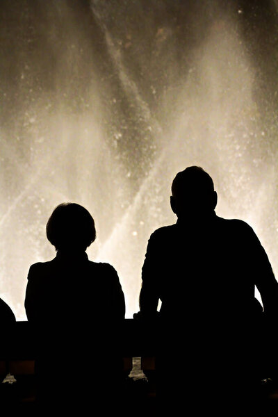 Night scene with silhouettes of people admiring the Bellagio fountains spectacle at Las Vegas