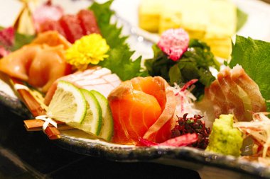 Japonya 'ya özgü otantik saşimi tabağı. Yeşil yapraklı çiğ balıklarla Japon yemek tarzı. Sinema tarzında hafif meşaleli.