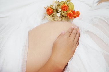 Hamile bir kadın beyaz arka planda yatakta uyuyor.   