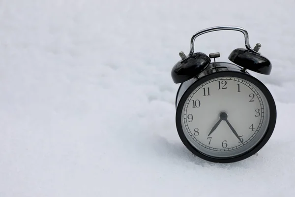 Relógio de alarme vintage no fundo branco de neve. Temporada de Inverno . — Fotografia de Stock