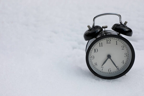 Vintage Alarm clock on snow white background. Winter season.