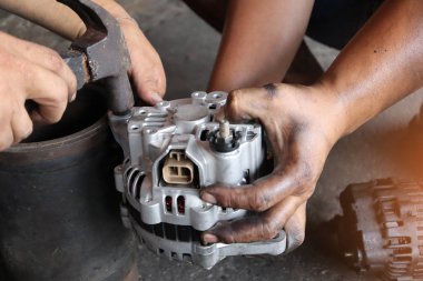 Change new car alternator with hand in the garage.