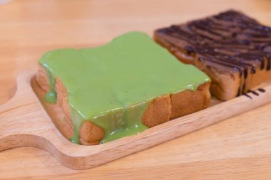 Ekmek üstte yeşil buğulanmış pandan muhallebi ile ahşap tepsi koymak