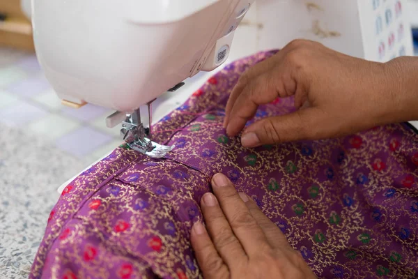 Woman sews strips of fabrics for the future silk shawl with sewing machine