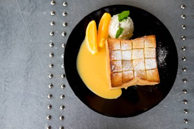 Bal Tost süslemeleri bir tarafı siyah çanak çırpılmış krema ve turuncu meyve dilimi