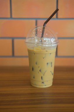 Cafe ahşap masa üzerinde plastik bardak buzlu kahve. Soğuk espresso.