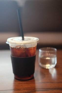 Siyah kahve plastik kap Cafe ahşap masa üstünde buz.