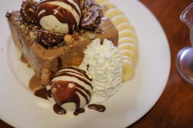 Masada beyaz tabak içinde dondurma ile muz ve bal tost dilim
