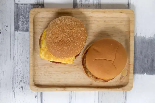 Tasty fresh pork burgers and egg muffin served on wooden tray