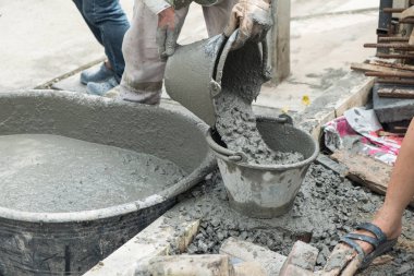 İşçi dökme çimento mix Beton inşaat sahasında kovada.