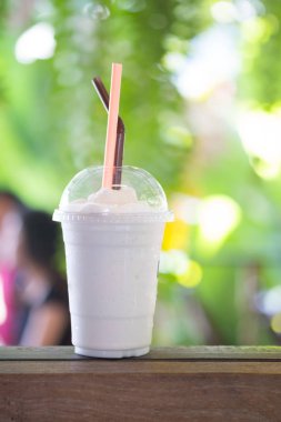 Ahşap masa üzerinde plastik bardak muzlu lezzetli taze süt