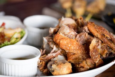 Bir tabakta sebze ve baharat soslu çıtır çıtır kızarmış domuz bacak yerleştirilir