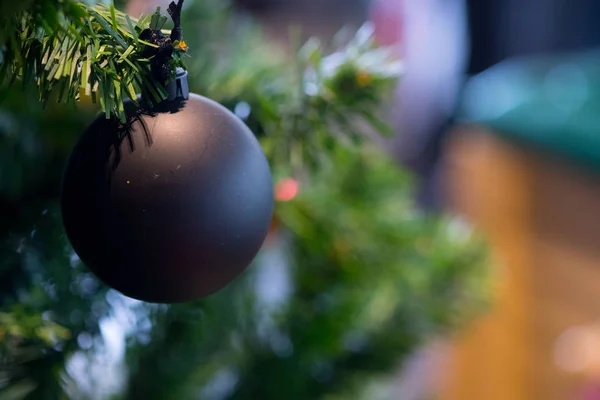 Black christmas ornaments hanging from christmas tree