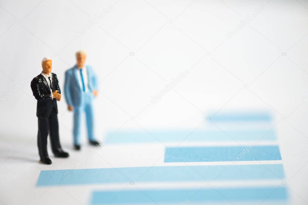 Miniature people businessmen analyze standing on graph with performance as background strategy concept and Business concept with copy space.