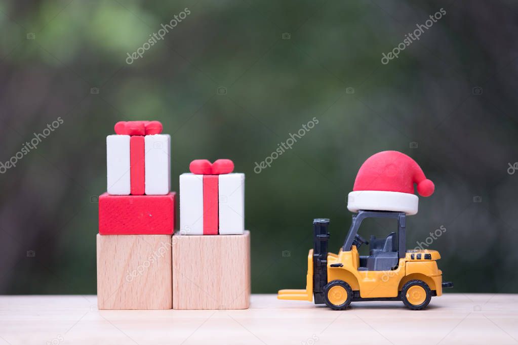 Hat Santa put on toy forklift truck with Christmas gift box. Gift delivery concept