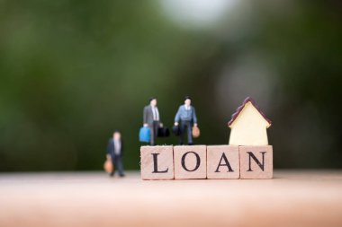 Minyatür insanlar işadamı ahşap word kredi ve arka plan olarak bulanık yeşil doğa ile ayakta. Ticaret ev kavramı