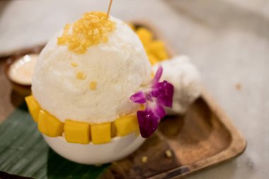 Tablo üzerinde şekerli yoğunlaştırılmış süt ile servis Bingsu mango