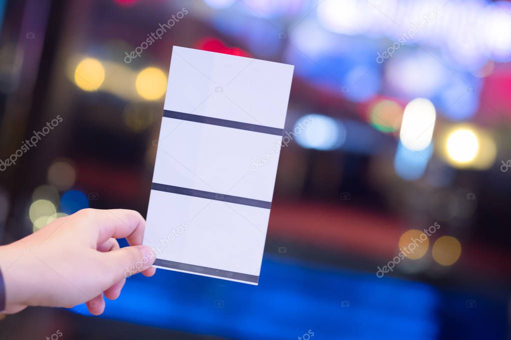 Hand holding three paper ticket on blurred background (booking ticket concept)