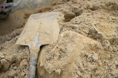 İnşaat işi için kum yığını üzerinde kürek. Şantiyede iş kavramı