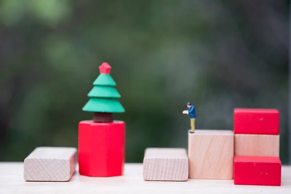 Miniature people standing on wooden  block manage Christmas tree Celebrate Christmas on December 25 every year