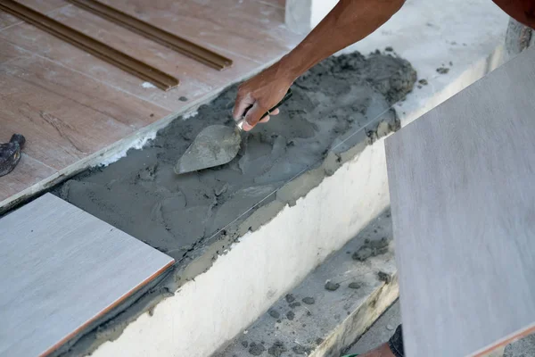Construction worker with plaster knife for floor renovation.Tiler installing ceramic tiles on a floor.